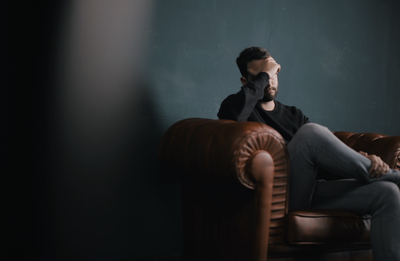 man sad and frustrated sitting on couch anxiety